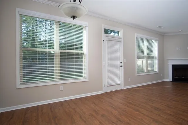 a view of an empty room with wooden floor and a window