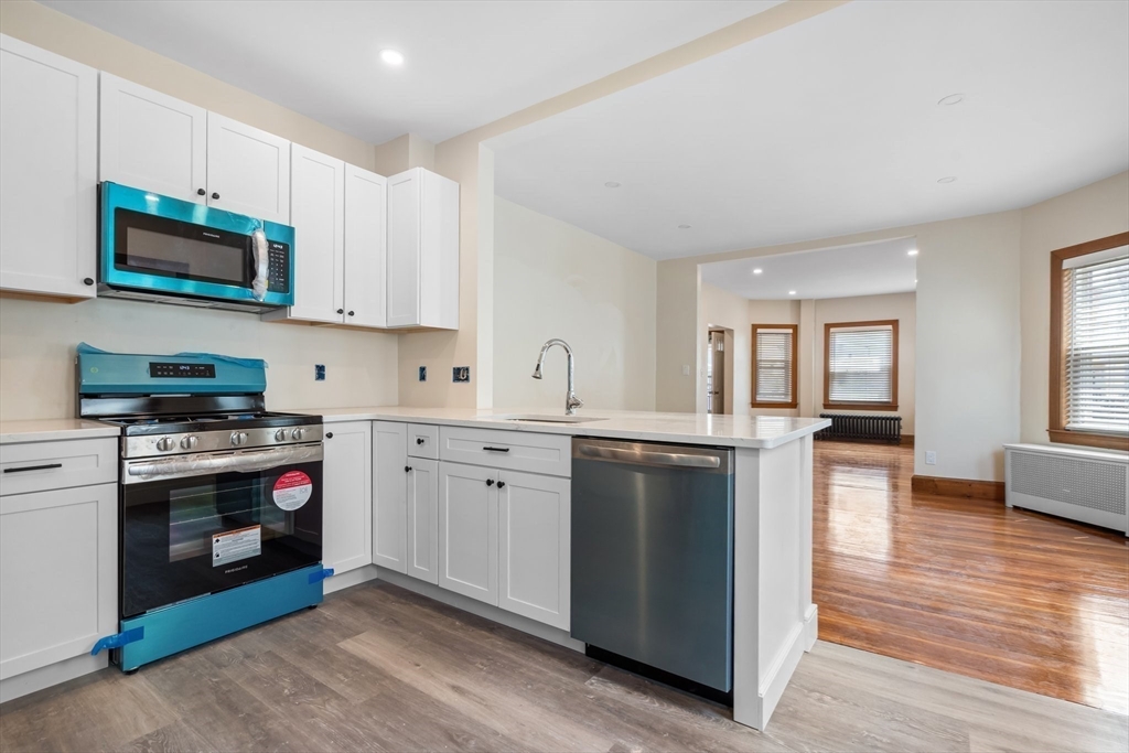 62 Vernal Street, Unit 3 Everett, MA 02149 - Photo 3 of 26 a kitchen with stainless steel appliances granite countertop a stove top oven a sink dishwasher and a microwave oven with wooden floor
