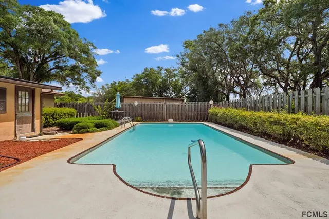 a view of a patio with table and chairs under an umbrella with a large tree
