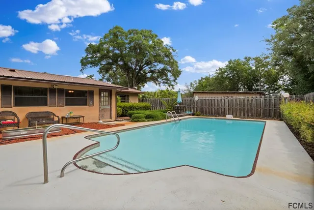 a view of a swimming pool with a patio and a yard
