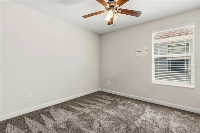an empty room with a window and a fan