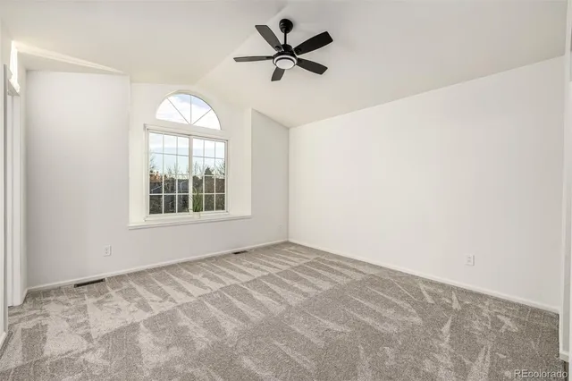 an empty room with a ceiling fan and window