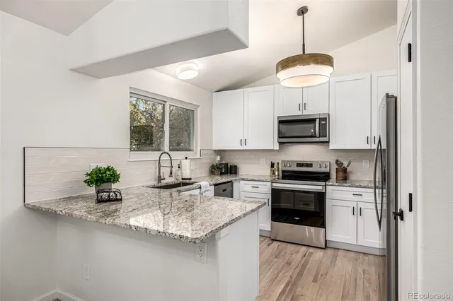 a view of a kitchen with wooden floor and stainless steel appliances