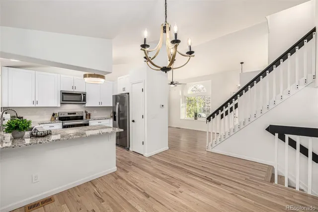a kitchen with a sink dishwasher a stove and white cabinets with wooden floor