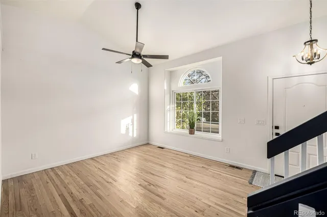 an empty room with wooden floor fireplace and windows