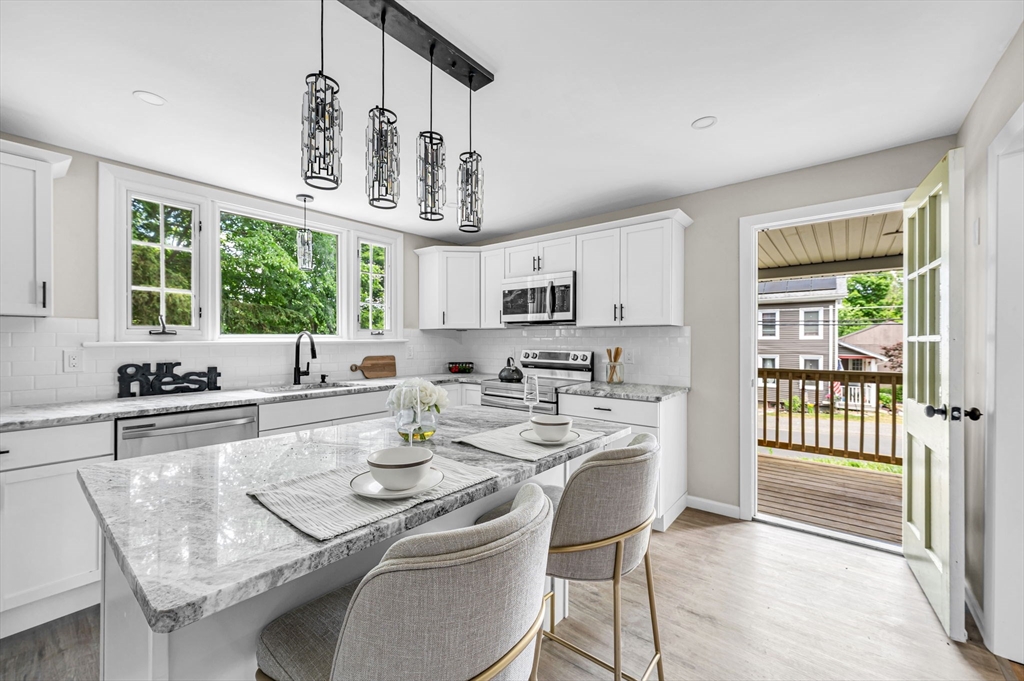 37 Bridge Street Monson, MA 01057 - Photo 33 of 35 a kitchen with stainless steel appliances granite countertop a stove a sink dishwasher a dining table and chairs with wooden floor
