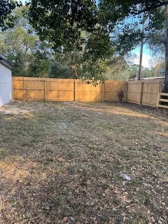 a view of backyard with wooden fence and trees