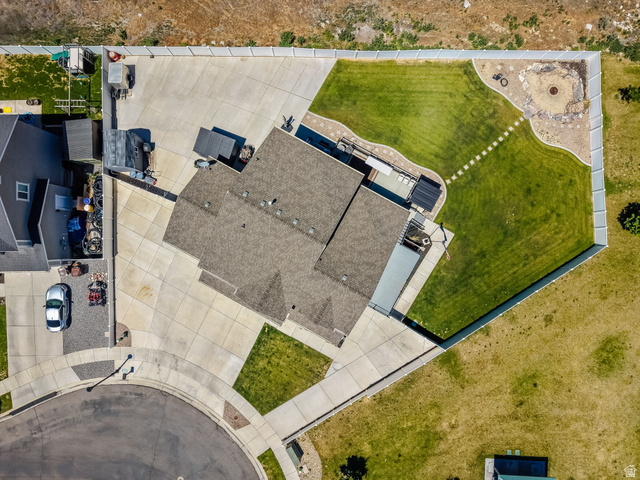 1857 Thunder Gulch Road Eagle Mountain, UT 84005 - Photo 49 of 50 Expansive concrete driveway and patio areas, manicured lawn, and a stone-lined fire pit feature