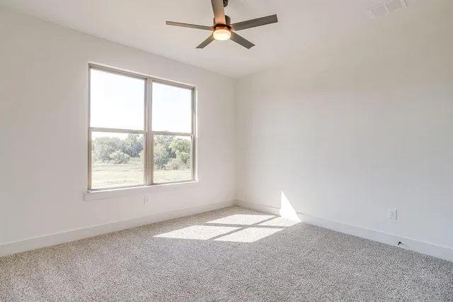 an empty room with a window and a fan