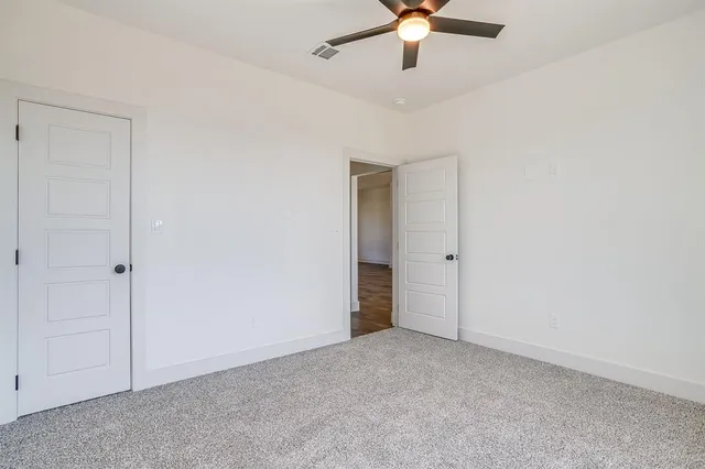 an empty room with closet and a chandelier fan