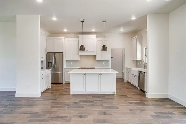 a large kitchen with a center island wooden floor stainless steel appliances and a window