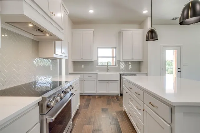 a kitchen that has a lot of cabinets in it and wooden floors