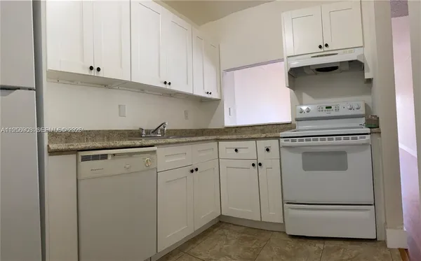a kitchen with granite countertop white cabinets and white appliances