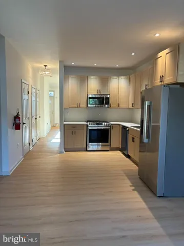 a large kitchen with stainless steel appliances kitchen island a large counter top and a refrigerator