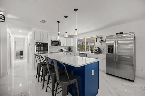 a kitchen with stainless steel appliances kitchen island granite countertop a table chairs sink and cabinets