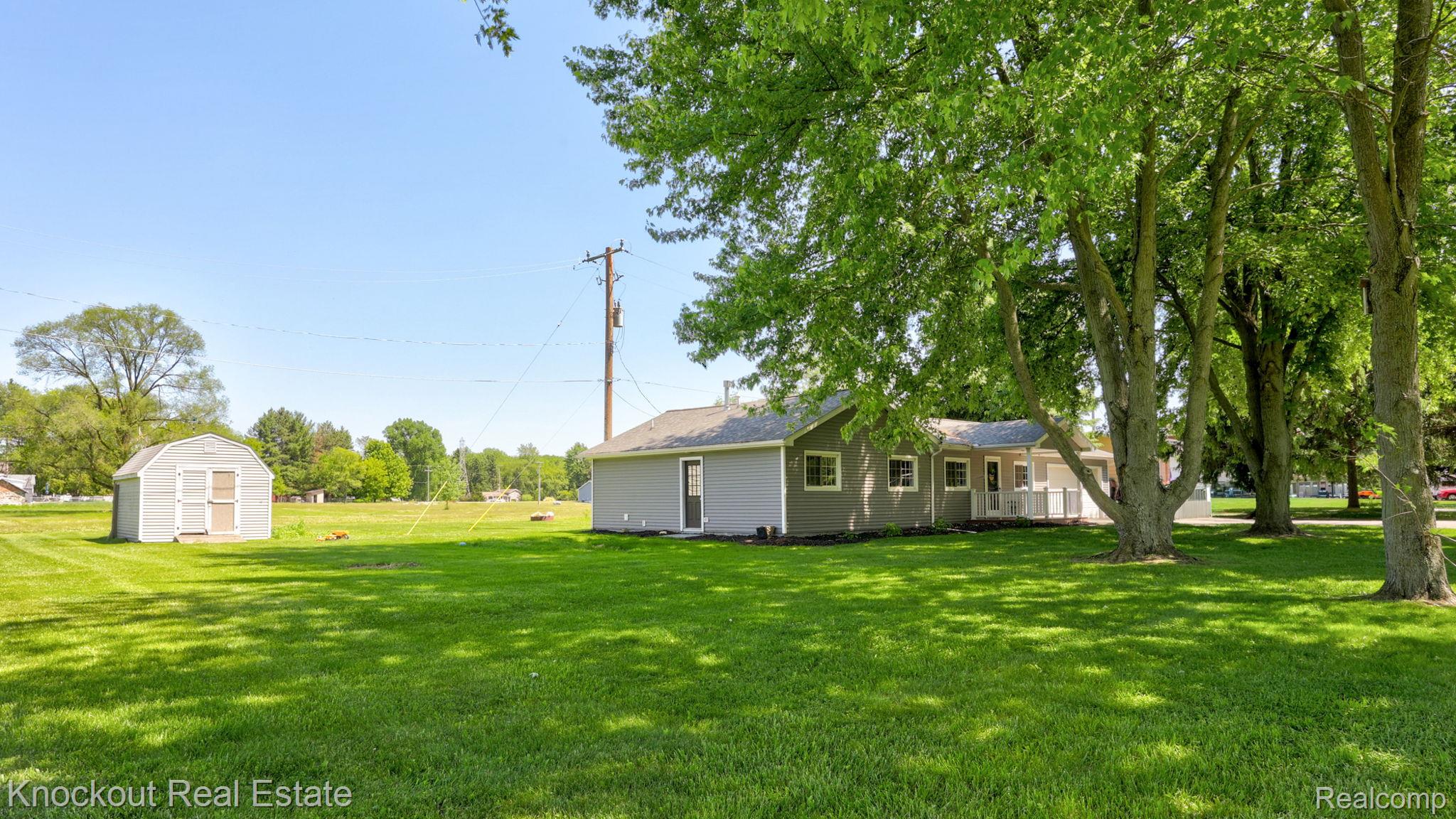 8845 Ormes Road Vassar, MI 48768 - Photo 34 of 35 Expansive green lawn with mature trees and a detached storage shed