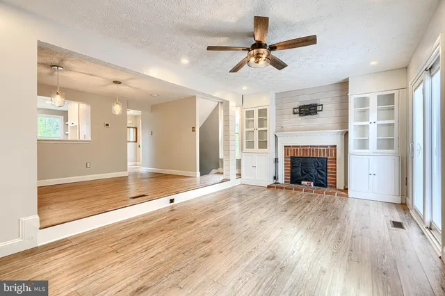 an empty room with wooden floor fireplace and windows
