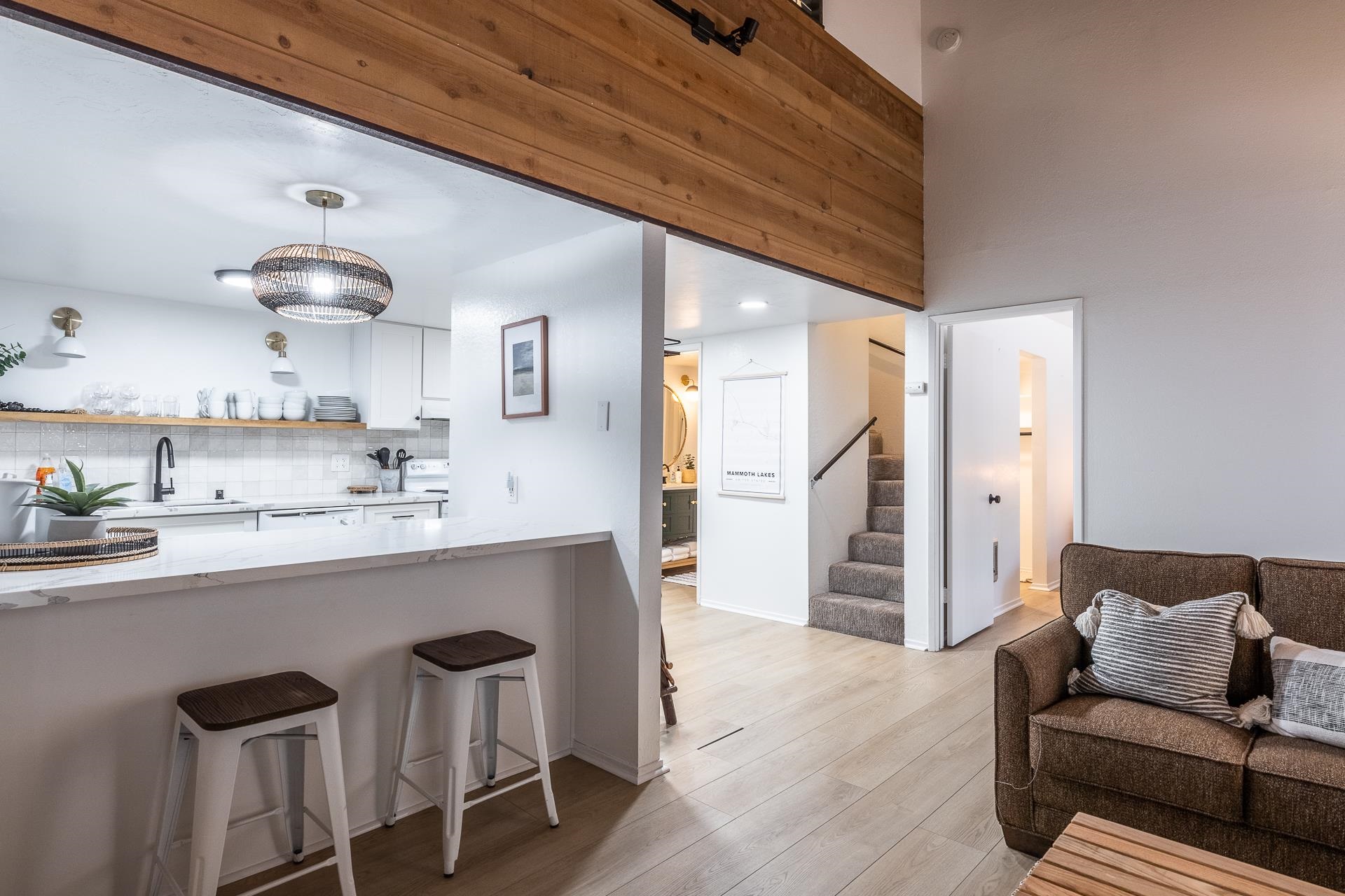 2289 Sierra Nevada Road, Unit J8 Mammoth Lakes, CA 93546 - Photo 16 of 30 Kitchen with hanging light fixtures, a kitchen breakfast bar, white cabinets, light wood-style flooring, and light stone countertops