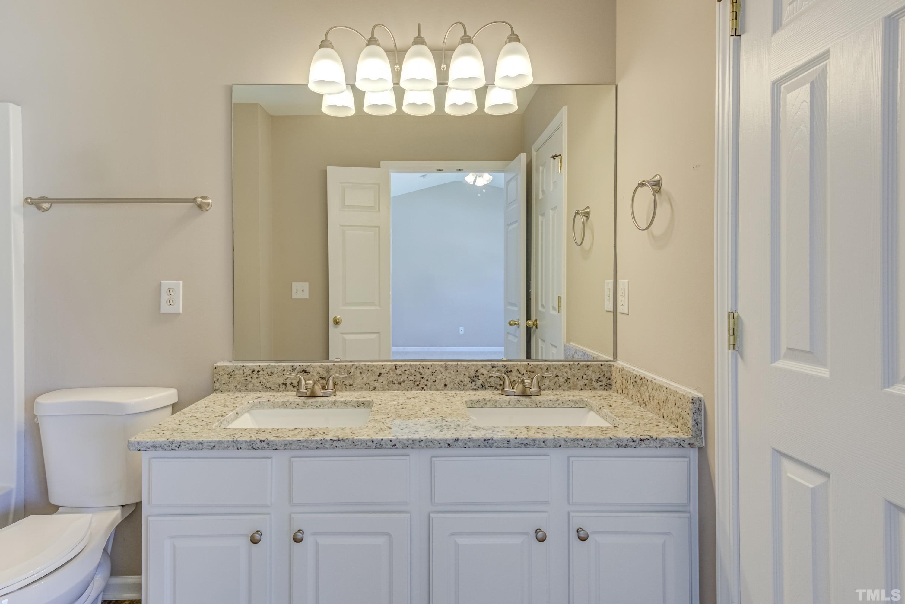 5328 Glen Canyon Road Raleigh, NC 27616 - Photo 23 of 35 a bathroom with a granite countertop sink a toilet and a shower