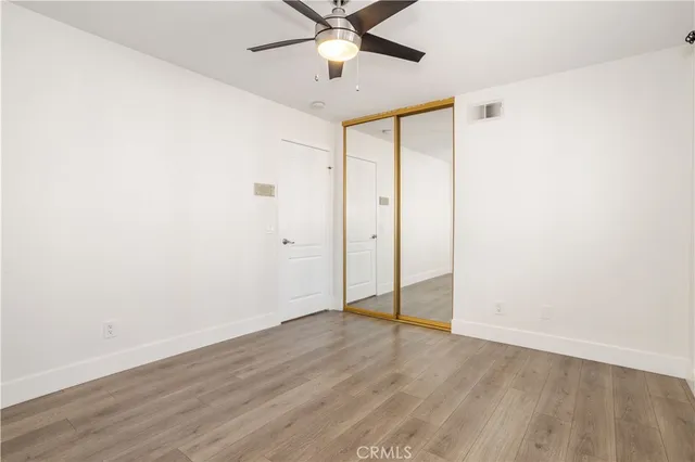 an empty room with wooden floor and fan