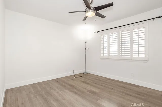 an empty room with wooden floor fan and windows