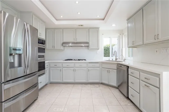 a kitchen with white cabinets stainless steel appliances and a window