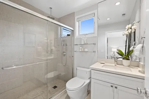 a bathroom with a granite countertop sink a toilet a mirror and shower