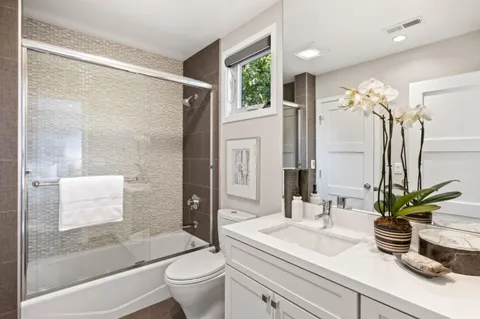 a bathroom with a granite countertop sink a toilet a mirror and shower