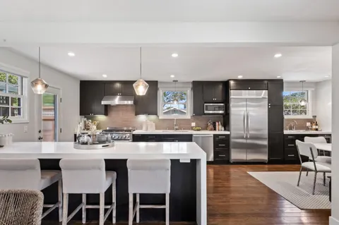 a kitchen with a dining table chairs refrigerator and microwave