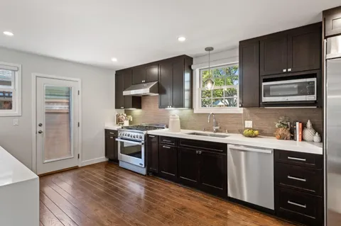 a kitchen with stainless steel appliances granite countertop a stove sink and cabinets