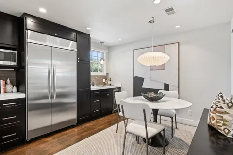 a kitchen with stainless steel appliances kitchen island granite countertop a refrigerator a stove a sink and a dining table with garden view