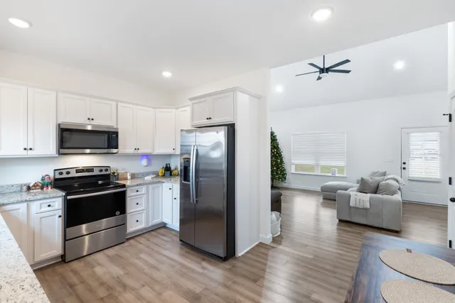 a kitchen with stainless steel appliances granite countertop a refrigerator a stove a sink and white cabinets