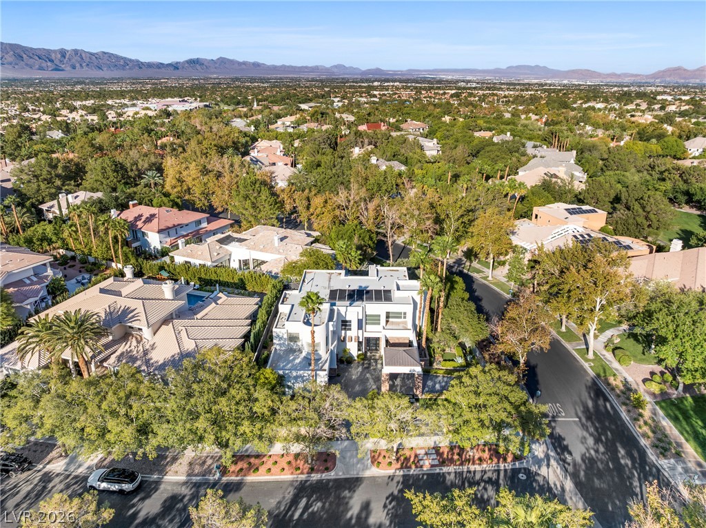 2000 Grouse Street Las Vegas, NV 89134 - Photo 81 of 89 An aerial panorama reveals a modern residence nestled within a verdant, tree-lined community with distant mountain backdrops.