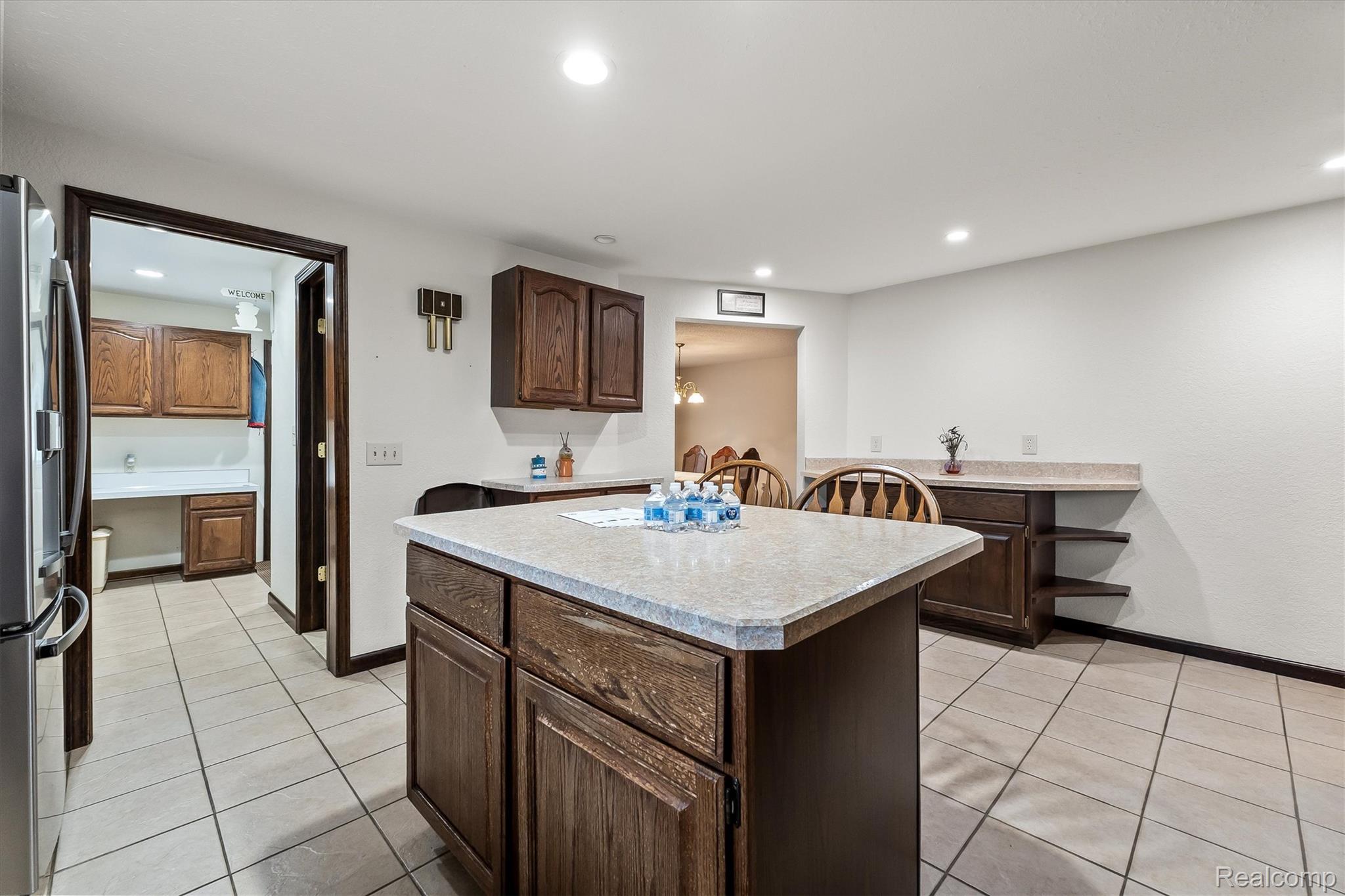 3553 North State Road Owosso, MI 48867 - Photo 13 of 45 Kitchen featuring a center island with a light-toned countertop, wood-finish cabinetry, tile flooring, recessed lighting, and a built-in stainless steel refrigerator