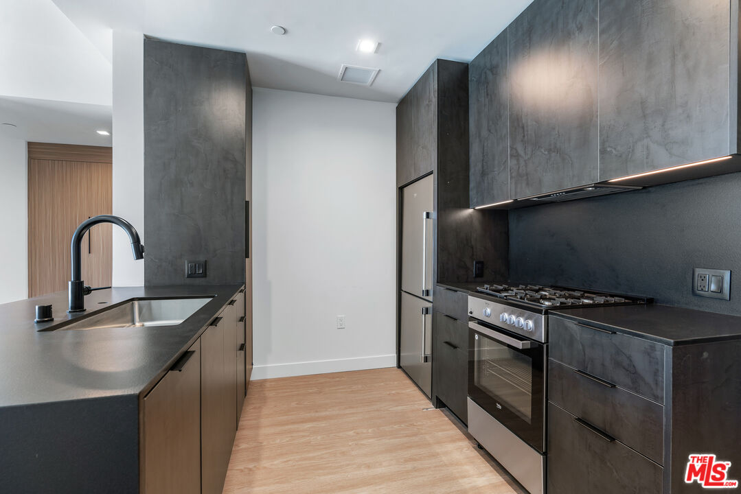 3688 Overland Avenue, Unit PH21 Los Angeles, CA 90034 - Photo 3 of 14 a kitchen with kitchen island stainless steel appliances a sink stove and refrigerator