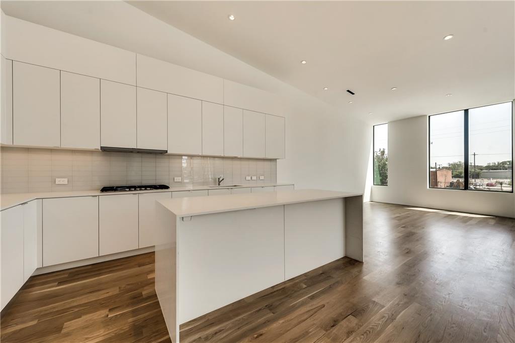 1504 Burlew Street, Unit 4 Dallas, TX 75204 - Photo 13 of 30 a kitchen with stainless steel appliances granite countertop a stove a sink and white cabinets with wooden floor