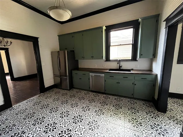 a kitchen with a sink a refrigerator and a mirror