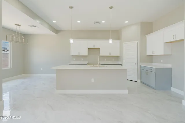 a large white kitchen with kitchen island a sink stainless steel appliances and cabinets