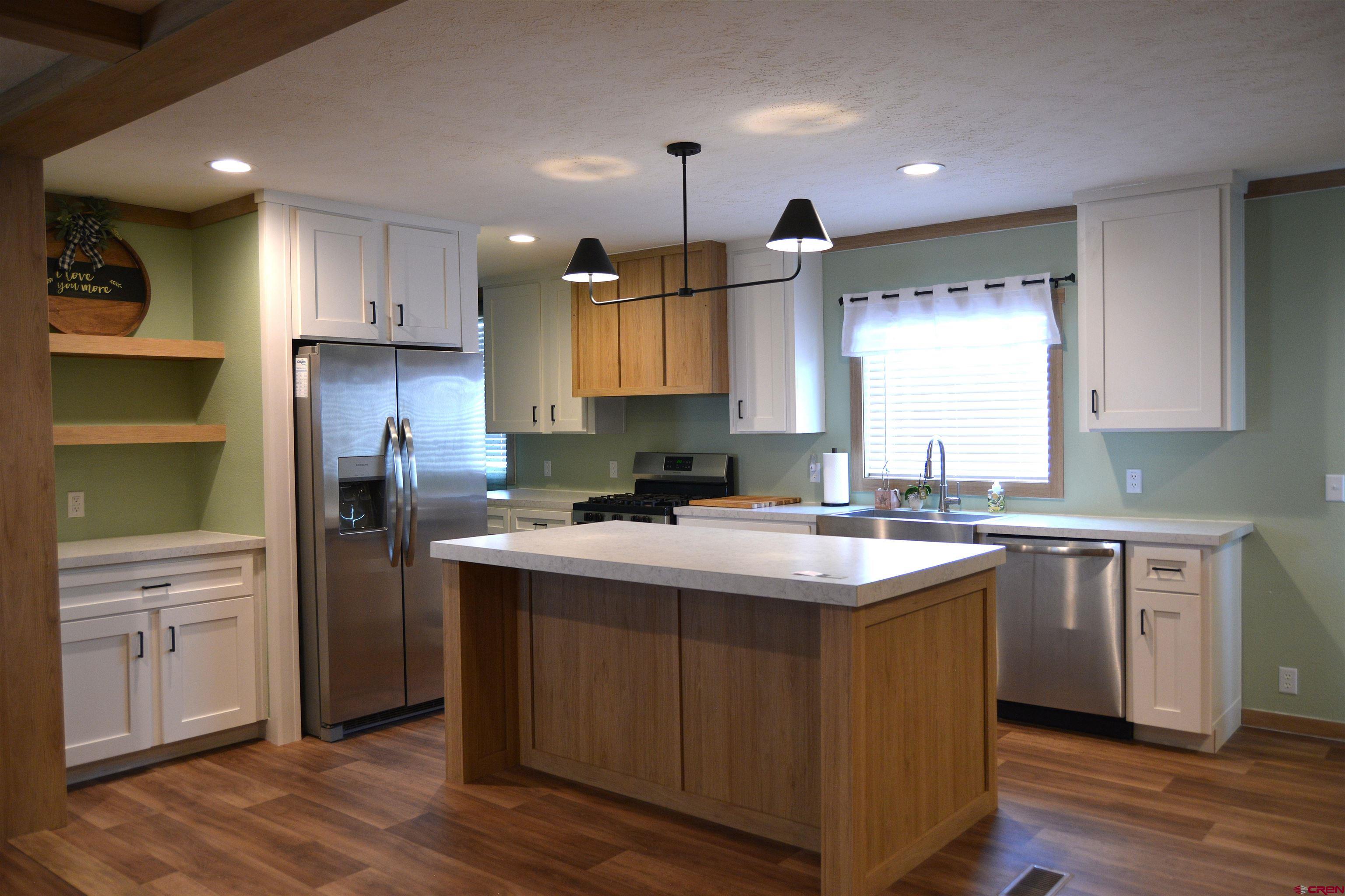 901 6530 Road, Unit 1030 Montrose, CO 81401 - Photo 4 of 22 a kitchen with kitchen island granite countertop a sink cabinets and wooden floor