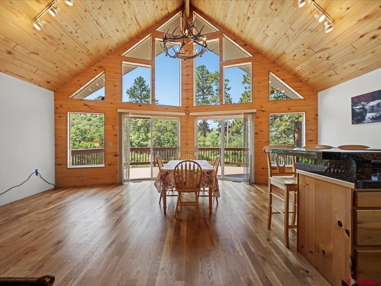 55 Valley View Road Ridgway, CO 81432 - Photo 6 of 40 a dining room with wooden floor a chandelier a glass table and windows