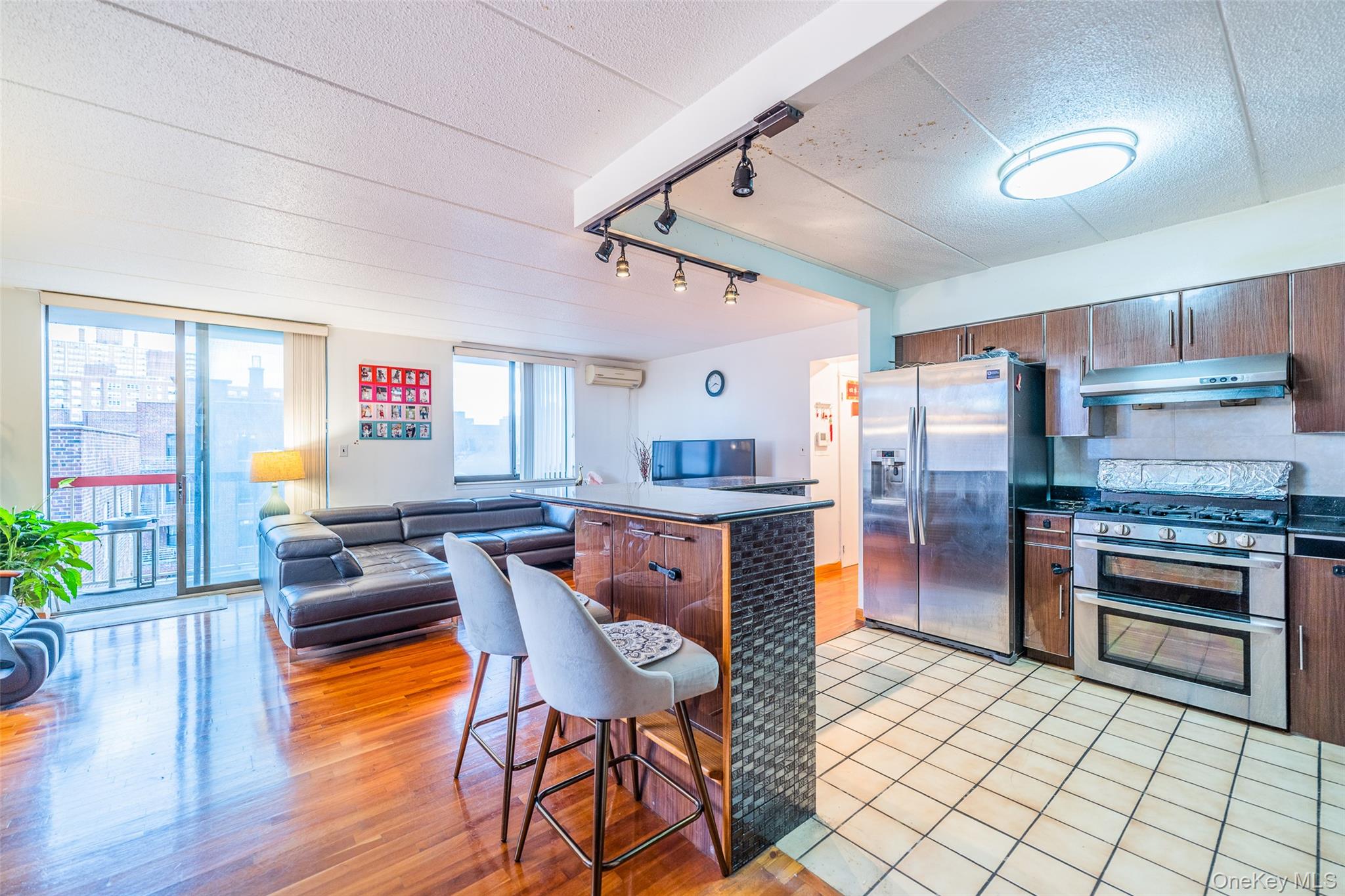 136-24 Maple Avenue, Unit 6F Queens, NY 11355 - Photo 28 of 29 a kitchen with stainless steel appliances granite countertop a stove top oven a refrigerator a dining table and chairs with wooden floor