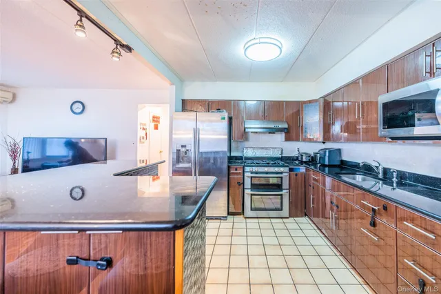 a kitchen with stainless steel appliances granite countertop a stove top oven a refrigerator a dining table and chairs with wooden floor