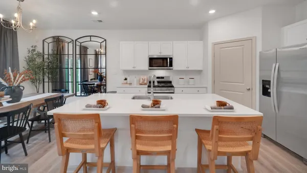 a kitchen with stainless steel appliances kitchen island granite countertop a table chairs and a refrigerator
