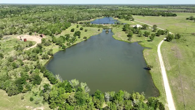 an aerial view of a residential houses with outdoor space and trees