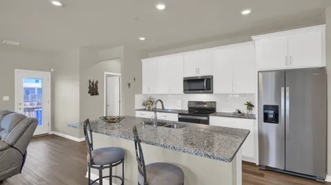 a kitchen with stainless steel appliances granite countertop a stove a refrigerator a sink a table and chairs