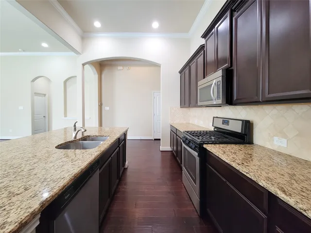 a kitchen with stainless steel appliances granite countertop a sink stove and refrigerator