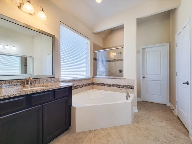a spacious bathroom with a granite countertop tub sink and mirror