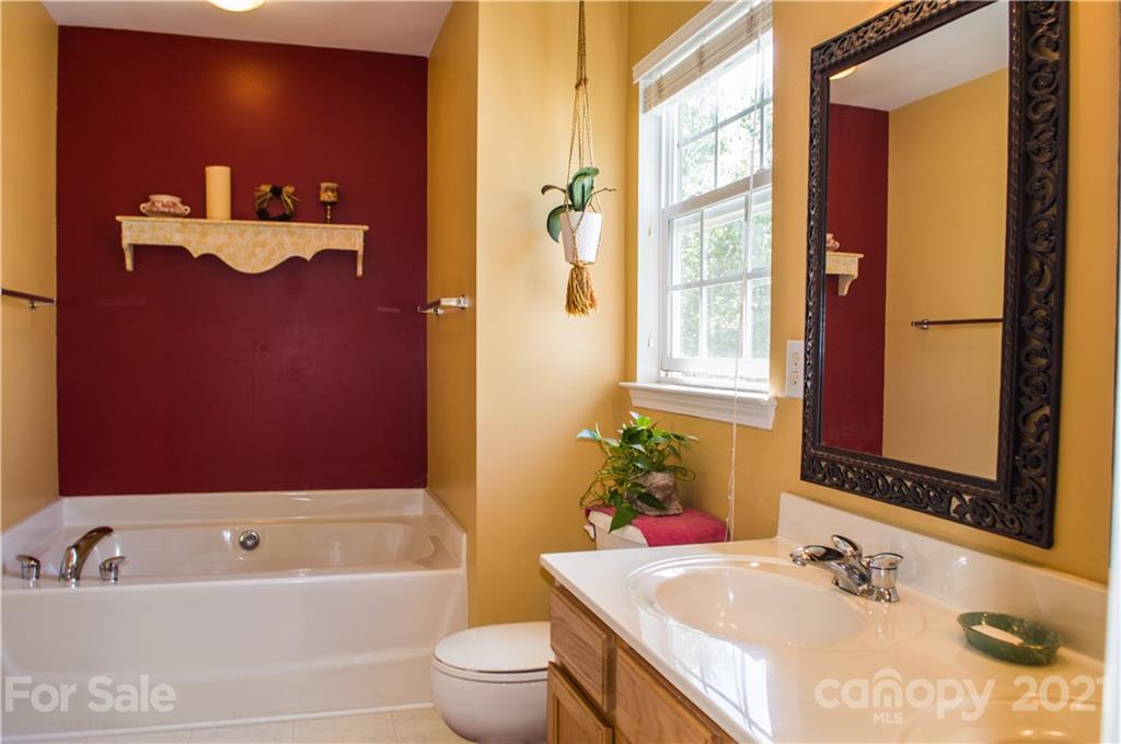144 Amber Woods Drive Tega Cay, SC 29708 - Photo 13 of 37 a bathroom with a granite countertop sink a mirror a bathtub and a shower