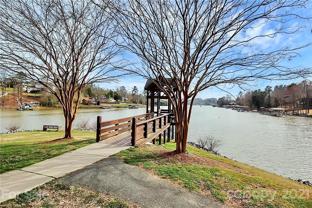 144 Amber Woods Drive Tega Cay, SC 29708 - Photo 21 of 37 a view of a lake with a bench next to a yard