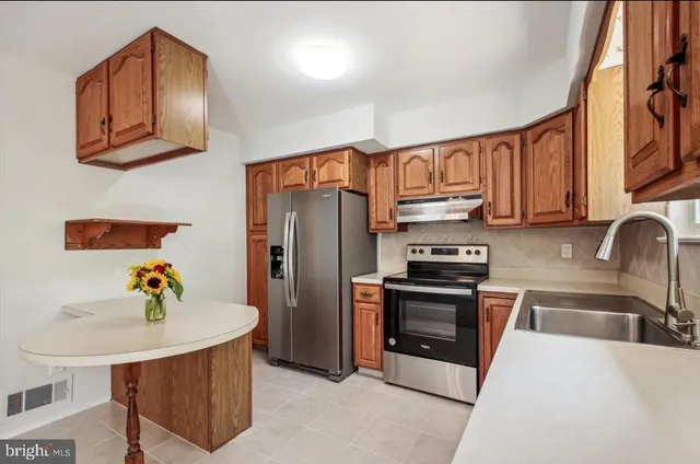 a kitchen with stainless steel appliances a sink a microwave a refrigerator and cabinets